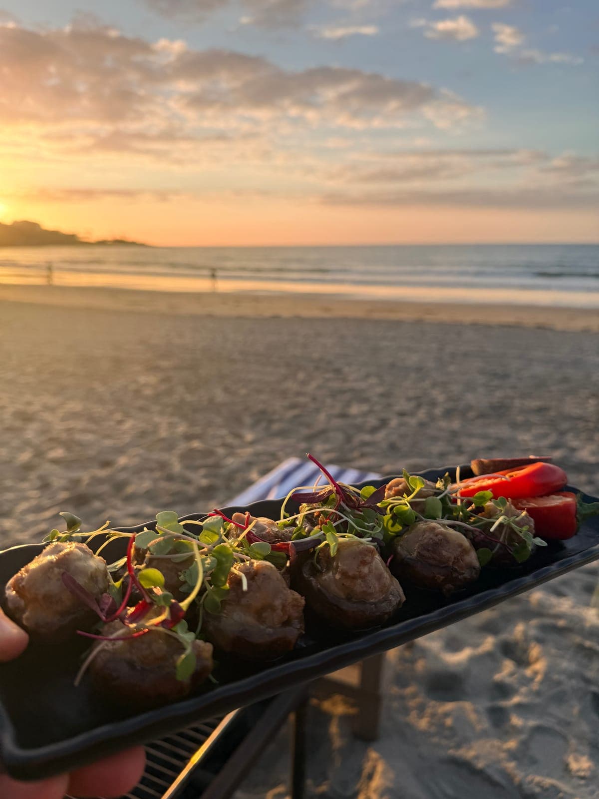 Lamb meatball appetizers with microgreens served on a San Diego beach at sunset